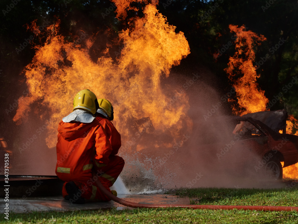 Poster firefighter spray water to fire burning car workshop fire training