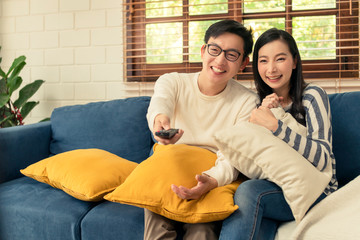 sweet asian marry couple happiness romantiv enjoy family moment at home wathching tv and enjoy recreation program on couch sofa home interior background