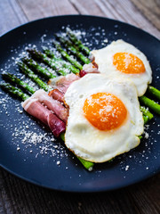 Sunny side up eggs with asparagus and parmesan on wooden background
