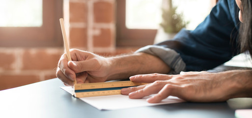 Close up of unrecognizable asian male architect or interior designer making measurements and designon housing new project