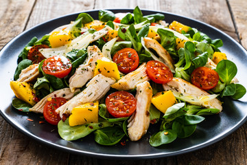 Caesar salad - fried chicken breast and vegetables on wooden table
