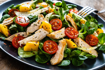 Caesar salad - fried chicken breast and vegetables on wooden table
