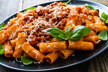 Tortiglioni with tomato sauce, meat and parmesan on wooden background