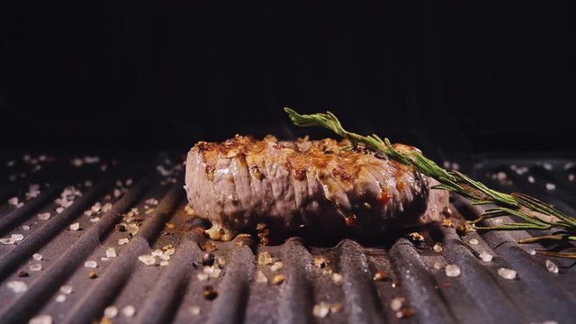 Delicious juicy meat steak cooking on grill. Aged prime rare roast grilling tenderloin fresh marble tenderness beef. Prime beef fry on electric roaster, rosemary, black pepper, salt. Slow motion.