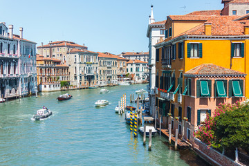 View of the Canal Grande (Venice, Italy) from the bridge on a summer day. Ancient buildings standing in emerald water, along which several boats sail.