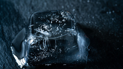 Close-up of melting blue ice cubes on black background