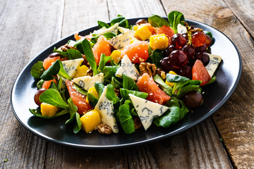 Fresh salad - blue cheese, fruit and vegetables on wooden table
