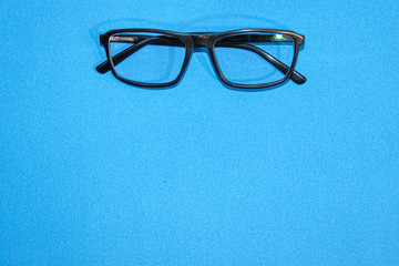 Black-rimmed glasses with diopters on a blue paper background.