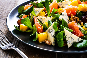 Fresh salad - blue cheese, fruit and vegetables on wooden table
