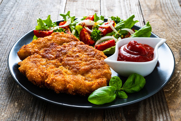 Pork chop with boiled potatoes and vegetable salad on wooden background