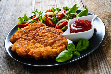 Pork chop with boiled potatoes and vegetable salad on wooden background