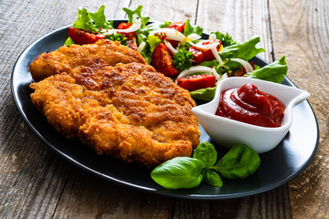 Pork chop with boiled potatoes and vegetable salad on wooden background