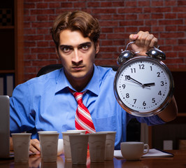 Young employee drinking coffee working at night shift