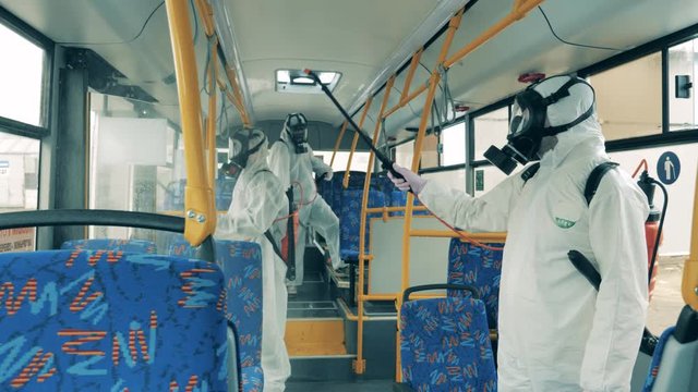 People in protective suits kill virus in a bus during disinfection.