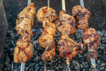 Cooking barbecue on a grill on a metal skewer. Grilled meat. Skewers of fresh chicken meat. Picnic, street food.