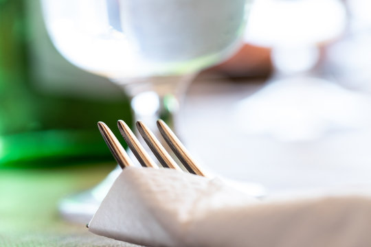 Lunch in a farmhouse in Puglia, in the south of Italy, during a hot summer day. Detail of a fork and a paper towel that wraps it on the background of a glass and a green bottle.