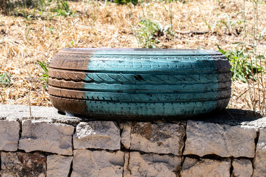 A Sunday in June on a farm in Puglia, a region of southern Italy. An old colored tire used as decoration for the garden under the sunlight.