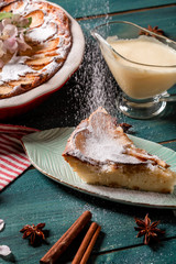 Apple pie with cinnamon on the table, a piece of apple pie with condensed milk on a white plate....