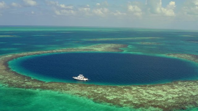 Aerial view of yacht in marine sinkhole against cloudy sky, scenic view of seascape - Great Blue Hole, Belize