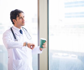 Young handsome doctor standing at the window