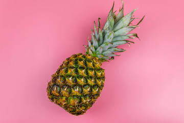 One whole pineapple on pink background. Top view