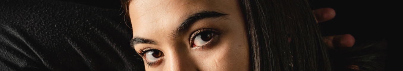 Obraz premium Low key close up of young woman with brown eyes.