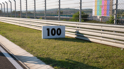 Warning sign or road sign for the maximum speed limit next to an empty road on a sunny summer day....