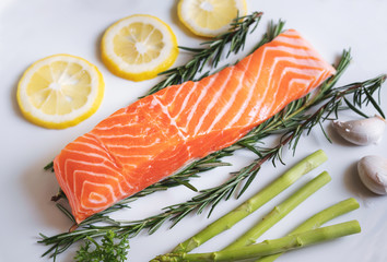 Raw fresh salmon fillet with herbs and ingredients, in white dish