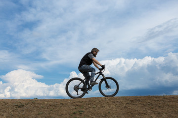 Sports brutal bearded guy on a modern mountain bike. A cyclist in a salt deserted place by the lake.