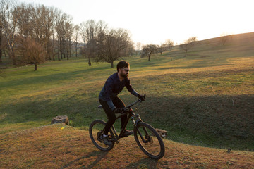 Fototapeta premium Cyclist in shorts and jersey on a modern carbon hardtail bike with an air suspension fork standing on a cliff against the background of fresh green spring forest
