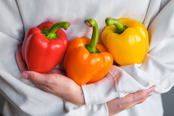 The girl holds colored bell pepper in her hands. Ripe fresh big sweet pepper. Healthy food, organic vegetables. Natural vitamins, raw ingredient for eating. Handpicked bio capsicum