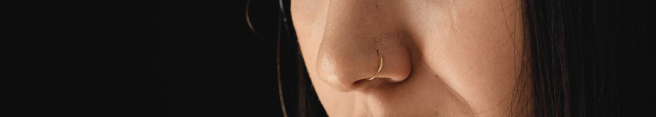 Fototapeta premium Low key close up of young woman with nose piercings