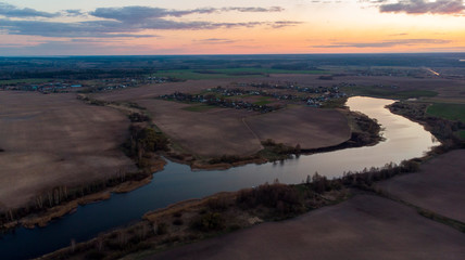 Aerial view at sunset over the river. Drone flying over the river at dawn in the fall. Panoramic views of the river and spring forest. Fog over water.