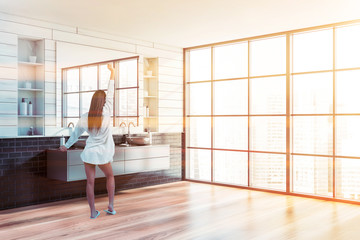Woman in white and brick bathroom with sink