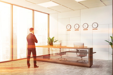 Man in white office with reception and clocks