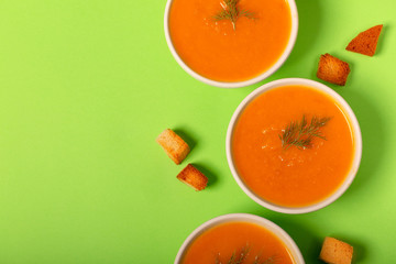 Pumpkin and carrot soup with fresh dill on green background