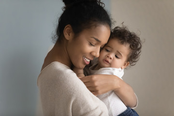 Close up of loving biracial young mom hug cuddle little ethnic infant toddler, happy caring african American mother embrace lull small baby girl child, enjoy tender moment, childcare concept