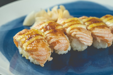 Salmon burned sushi with cheese on blue dish