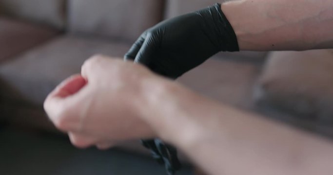 Slow motion man hands put on black nitrile protective gloves indoors