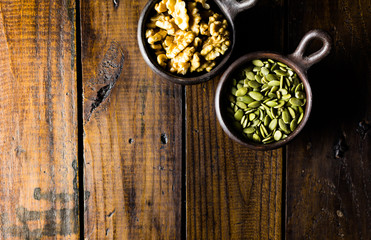 Fototapeta na wymiar Variety of nuts, seeds and granola in a clay pots with a beautiful wooden rustic background. Healthy concept. Vegan Concept. Copy space. Top view