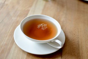 fresh cup of golden darjeeling tea on wooden breakfast table in white porcelain 
