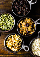 Variety of nuts, seeds and granola in a clay pots with a beautiful wooden rustic background. Healthy concept. Vegan Concept. Copy space. Top view