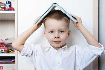 Adorable Toddler Boy With Book On Head.