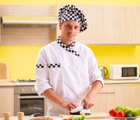 Young professional cook preparing salad at kitchen