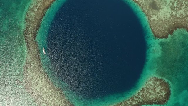 Aerial top view of yacht in marine sinkhole on sunny day, scenic view of seascape - Great Blue Hole, Belize
