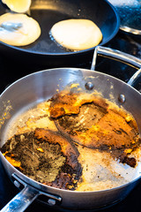 steel stewpan with remains of burned while cooking pancakes on electric stove in home kitchen
