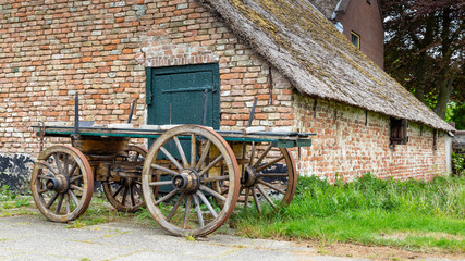 Fototapeta na wymiar Traditional Dutch farm with thatched roof and an ancientwooden wagon