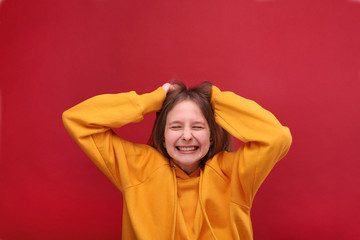 A beautiful girl holds her hair and smiles.