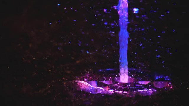 Splashes of fountain. Slow motion of water illuminated in colorful falling on fountain which change it water color in night. Wonderful multicolored fountain throws up high streams of sparkling water.