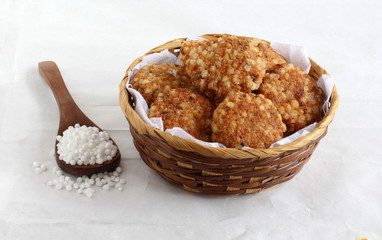 Sabudana vada, made from sago, is a traditional, popular, delicious, and vegetarian snack, native to Maharashtra, India, in a basket, and sago on a wooden spoon.